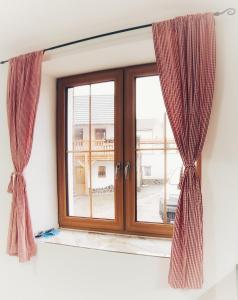 una ventana con cortinas de color burdeos en una habitación en Moravský Grunt Konírna, en Olomouc