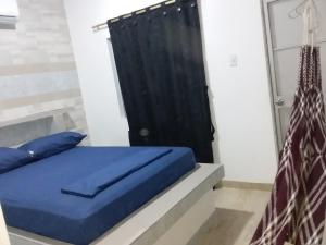 1 cama con almohadas azules y cortina negra en HOSTAL KASHI KAI, en San Juan del Cesar
