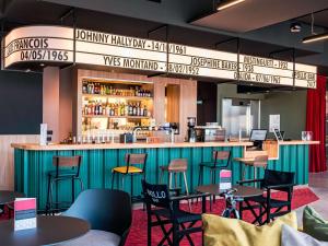 um restaurante com um bar com mesas e cadeiras em ibis Styles Lens Centre Gare em Lens