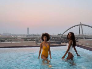 dos mujeres en una piscina en la parte superior de un edificio en ibis Styles Dubai Deira, en Dubái