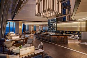 珠海的住宿－珠海横琴希尔顿逸林酒店，酒店大堂设有酒吧和桌椅