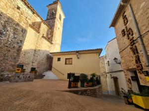 a building with a clock tower in a courtyard at Ático Rural en pareja, amigos o familia a la montaña "EL COLMENAR" in Chóvar