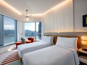 two beds in a room with a large window at Mondrian Hong Kong in Hong Kong