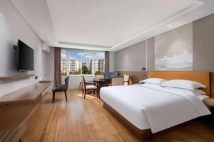 a bedroom with a large white bed and a dining room at Days Inn by Wyndham Kunming Airport Economic Zone in Kunming