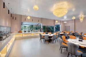 a restaurant with tables and chairs and a kitchen at Days Inn by Wyndham Kunming Airport Economic Zone in Kunming