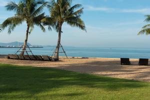 two palm trees and benches on a beach with the ocean at ไวท์ แซนด์ บีช เรสซิเดนซ์ พัทยา(White Sand Beach Residences Pattaya) in Na Jomtien