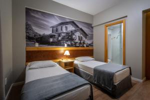 una habitación con 2 camas y una pintura de una casa en Brivali Hotel e Eventos en Caçador
