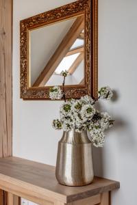 a vase with flowers on a shelf in front of a mirror at Wellness apartmány Český ráj & Biokolna in Lomnice nad Popelkou