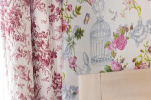 a curtain with a bird cage on a wall with flowers at Hôtel de Lion sur Mer in Lion-sur-Mer