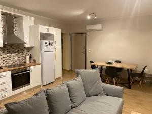een woonkamer met een bank en een keuken met een tafel bij Lovely apartment 2’ walking from Anavyssos beach in Anavissos
