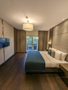 a bedroom with a large bed and a large window at Palm Meadows Resort in Bangalore
