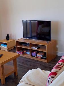 TV de pantalla plana en un centro de entretenimiento de madera en Simon's Place is a 3 bedroom bungalow in H.T.H en Jamestown