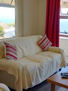 um sofá branco com duas almofadas sentadas em frente a uma janela em Simon's Place is a 3 bedroom bungalow in H.T.H em Jamestown