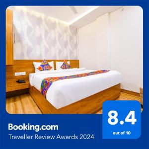 Habitación de hotel con cama con sábanas blancas en FabHotel Woodlark Inn, en Indore