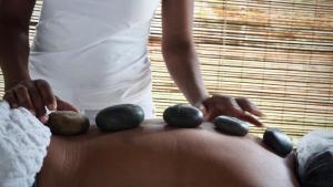 una mujer está poniendo piedras en su estómago en Soleluna Casa Pousada, en Trancoso