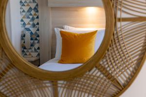 a mirror reflection of a bed with a yellow pillow at Hôtel de Lion sur Mer in Lion-sur-Mer
