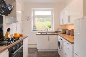 a white kitchen with a sink and a stove at The Nest by Afan Valley Escapes in Port Talbot