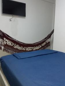 una camera con letto con lenzuola blu e TV a schermo piatto di HOSTAL KASHI KAI a San Juan del Cesar