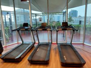a gym with three treadmills in a room with windows at Spacious, Economical Apt Near Miralcz Garden in Dubai