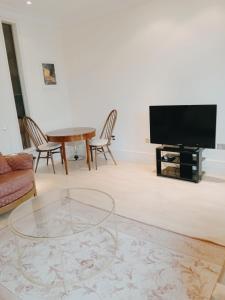 a living room with a tv and a table and chairs at Luxury apartment London Kew National Archives in London