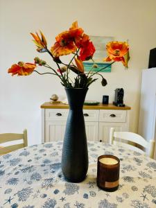 un vase noir avec des fleurs orange sur une table dans l'établissement GRADISSIMO, à Grado-Pineta