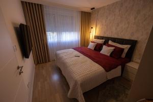 ein Schlafzimmer mit einem großen Bett mit roten und weißen Kissen in der Unterkunft Vividlux Apartments in Aranđelovac