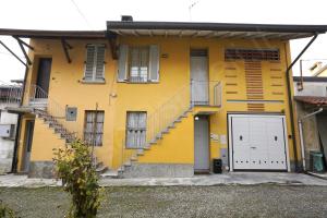 a yellow building with stairs and a white door at Case Ospitali - Corte Nuova appartamento in corte storica con due camere e due bagni in Caponago