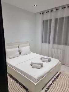 a white bedroom with a large bed with two towels on it at S+1 très haut standing avec piscine et fitness in Sidi Daoud