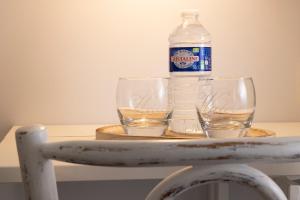 a bottle of water and two glasses on a table at Hôtel de Lion sur Mer in Lion-sur-Mer