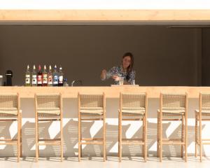 Uma mulher está atrás de um bar com cadeiras. em Sergios Hotel em Hersonissos