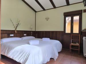 a bedroom with two beds with white sheets and a window at Masia Del Cura in Rubielos de Mora