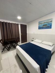 a bedroom with a large bed and a chair at suites com cozinha compacta in Cabo Frio