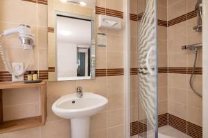 a bathroom with a sink and a shower at Hôtel de Lion sur Mer in Lion-sur-Mer