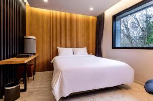 1 dormitorio con 1 cama blanca grande y escritorio en For You self service motel, en Jeju