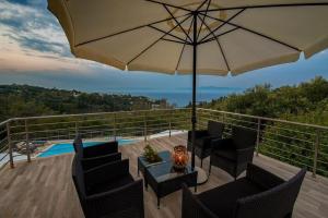 a patio with an umbrella and chairs and a table at Elisabetta Villa by PaxosRetreats in Gaios