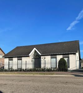 une maison blanche avec un toit noir et une clôture dans l'établissement Vakantiewoning Villa 35, à Maasmechelen