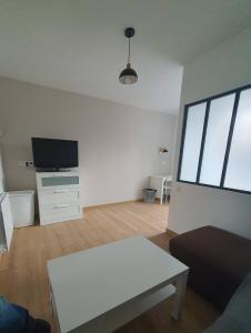 HéricourtにあるLe Coquelicot : appartement T1のソファとテレビのあるリビングルーム