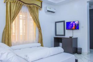 a living room with two white beds and a television at Marathona Shortlets Abuja in Abuja