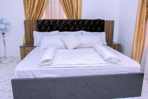 a large bed with white sheets and pillows on it at Marathona Shortlets Abuja in Abuja