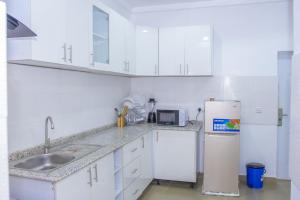 a white kitchen with a sink and a refrigerator at Marathona Shortlets Abuja in Abuja +15 photos