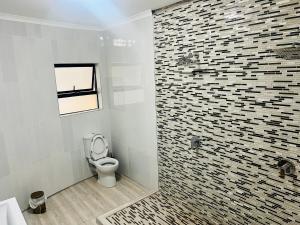 a bathroom with a toilet and a tile wall at Zindiza Guesthouse 2 in Del Judor
