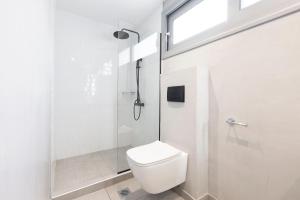 a white bathroom with a toilet and a shower at San Panteleimon in Paralia Panteleimonos