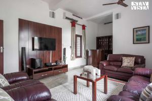 a living room with leather furniture and a flat screen tv at StayVista at Periyar Palace- Pet Friendly, River View Villa with Garden in Cochin