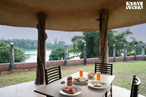 a table and chairs with a view of a river at StayVista at Periyar Palace- Pet Friendly, River View Villa with Garden in Cochin