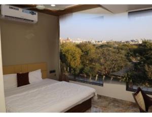 a bedroom with a bed and a large window at Hotel The Pill, Bhavnagar in Bhavnagar