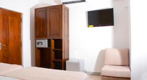 1 dormitorio con 1 cama, TV y silla en Inlak Garden Hotel en Negombo