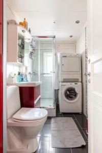 a bathroom with a toilet and a washer and dryer at Cosy room in a family flat in Oslo
