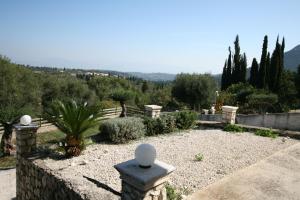 un jardín con una valla de piedra, árboles y árboles en Corfu Luxury Apartment, Tranquility, Mountain & Sea Views en Agios Gordios