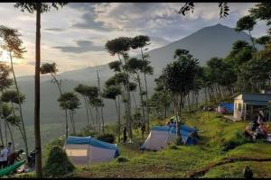 un grupo de tiendas de campaña en una colina con una montaña en Wong Deso Camping, en Seminyak