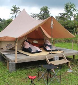 a tent with a table and a chair in a field at Wong Deso Camping in Seminyak